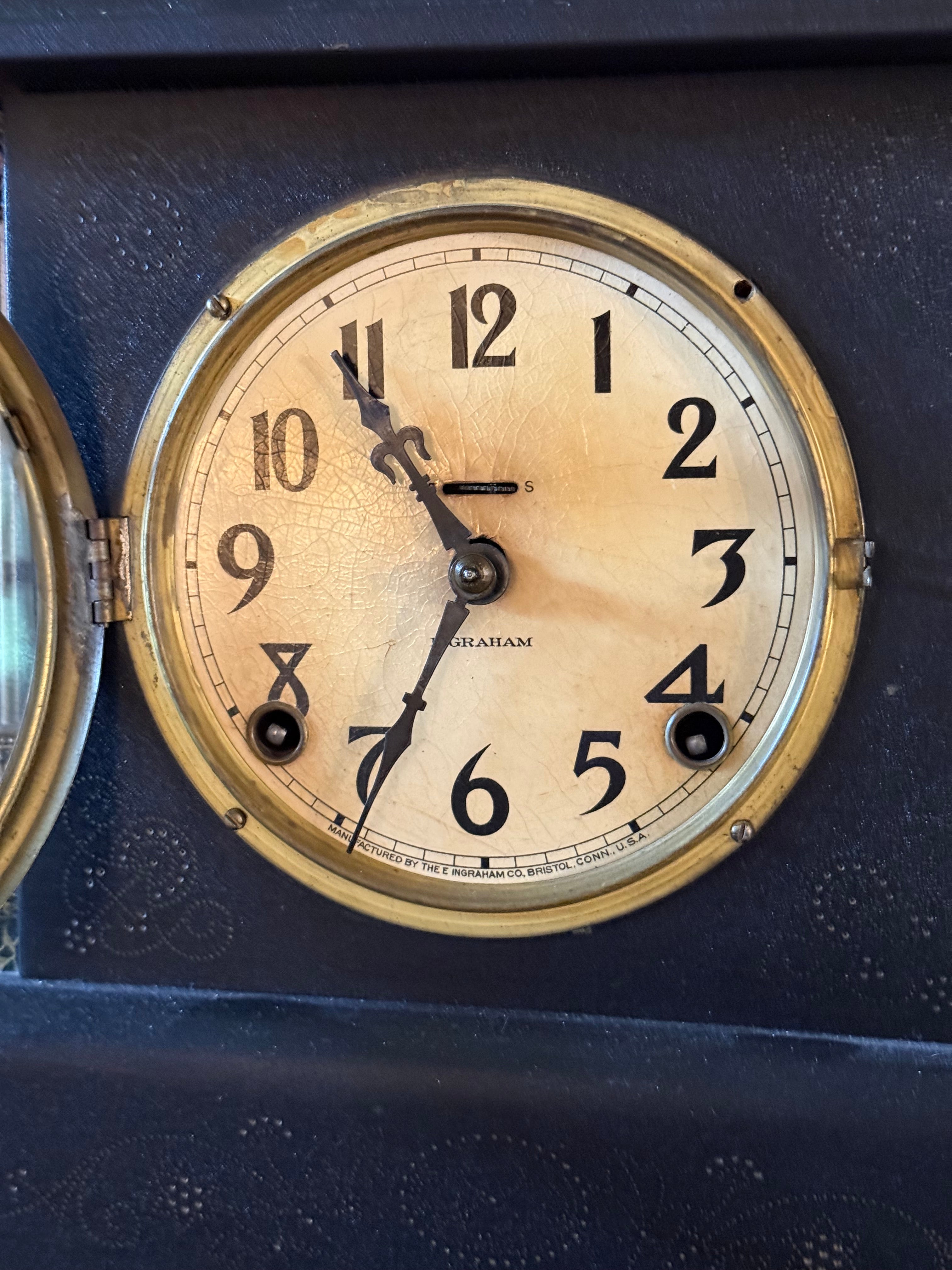 Close-up of a vintage wall clock face with a round beige dial, black Arabic numerals, black hands, and a gold-toned metal frame, set against a dark blue textured background.