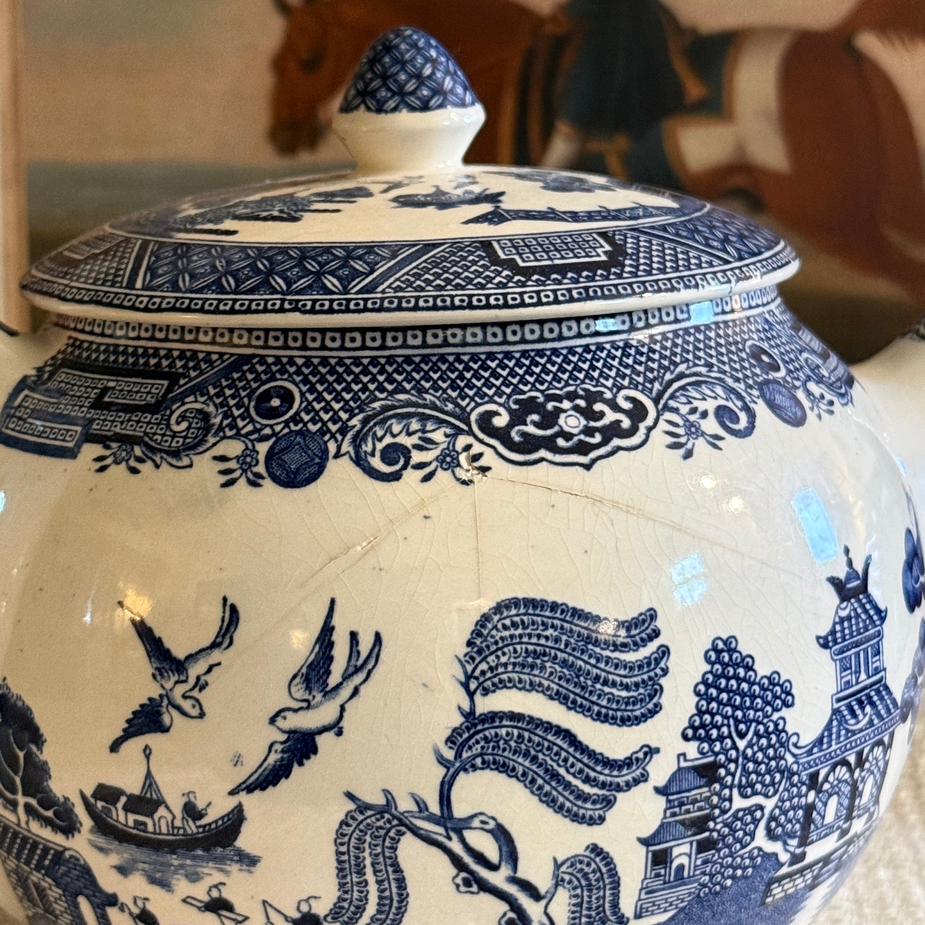 Close up of a hairline crack on the side of a vintage Blue Willow teapot for condition disclosure