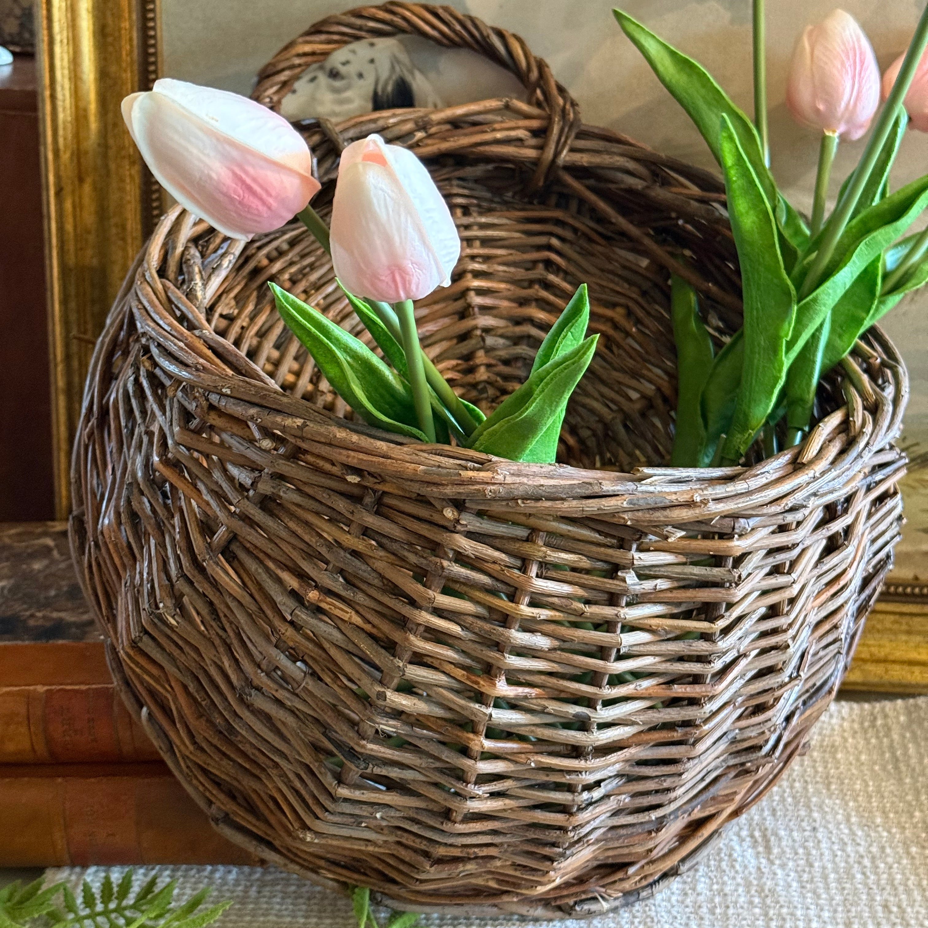 Wicker basket with pink tulips against a neutral background