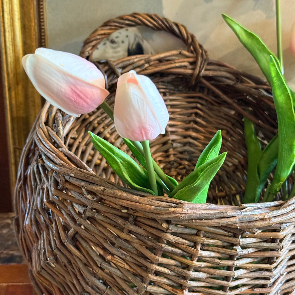 Wicker basket with pink tulips on a textured surface