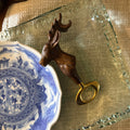 Decorative deer bottle opener shaped like a deer head on a blue and white ceramic plate.