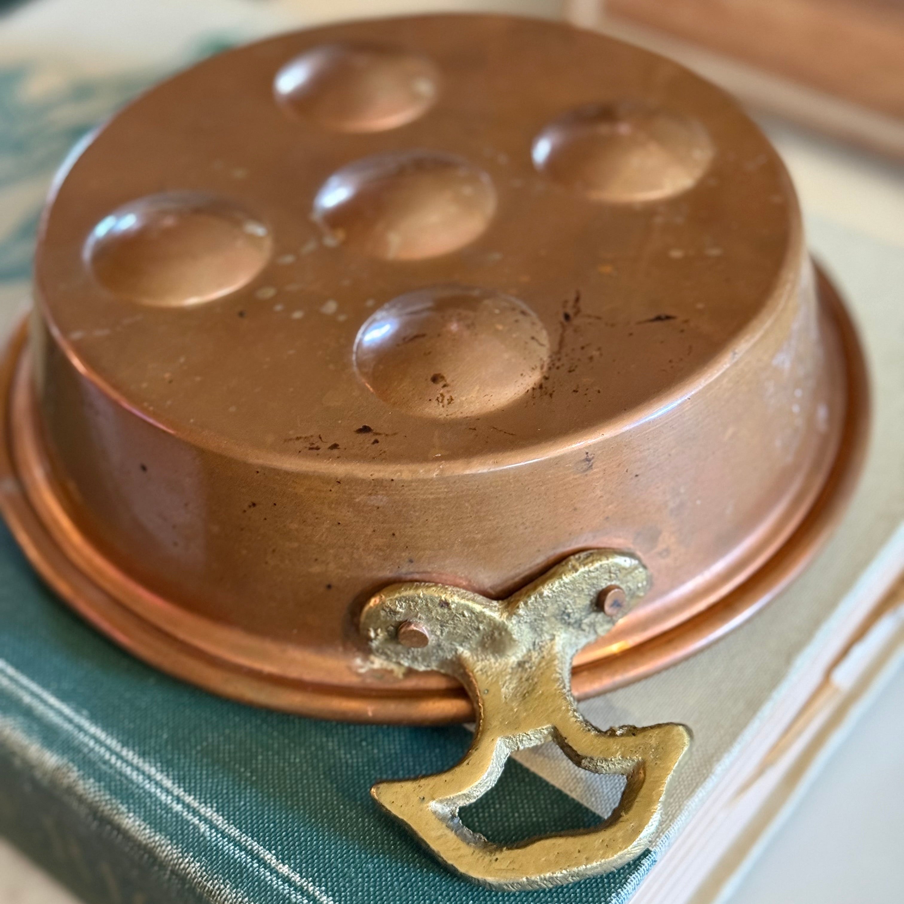 Detail view of the ornate brass handles on a traditional Turkish copper poacher.