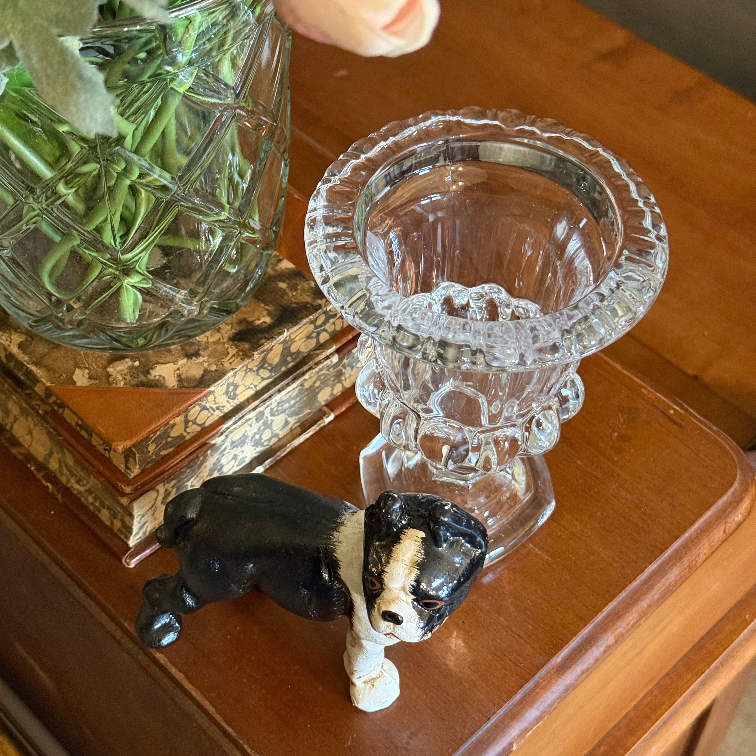 Side profile of the small crystal urn vase on a wooden surface, highlighting the decorative vertical facets and footed base.