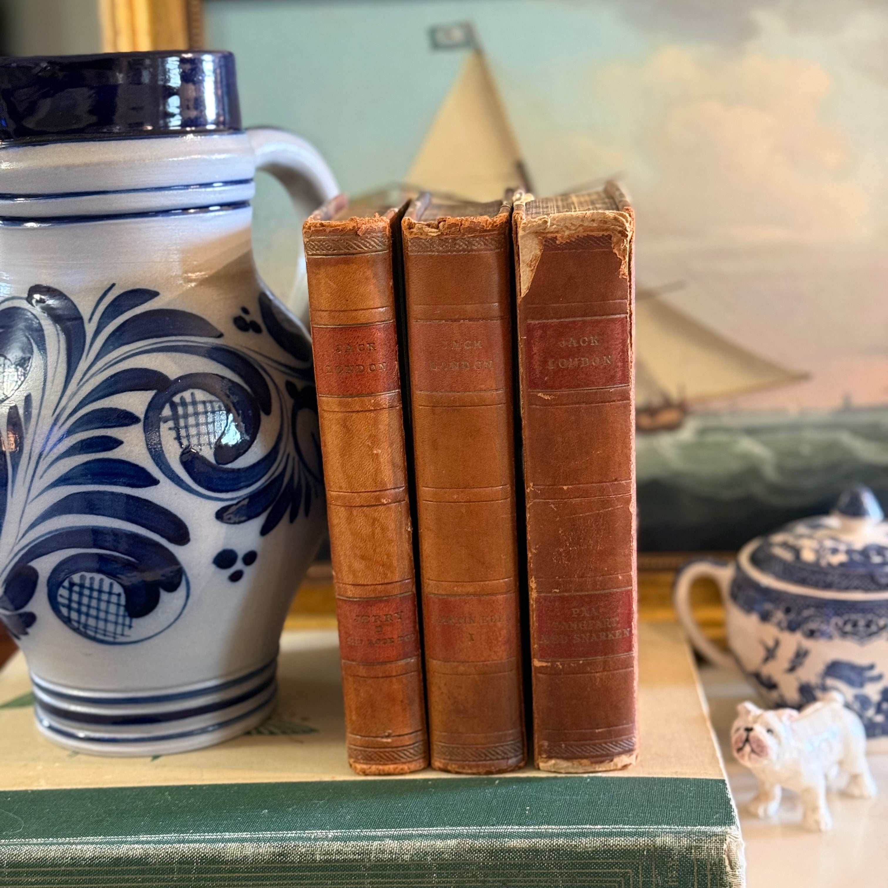 Close up of three cognac leather book spines with gold stamped Danish titles