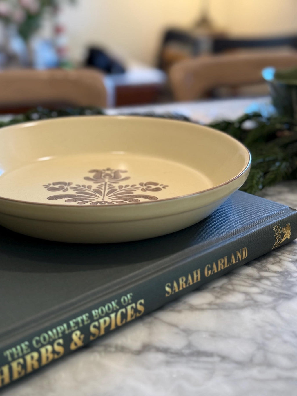 1970s Pfaltzgraff Village ceramic pie baking plate, Made in USA. Cream-colored stoneware with a brown floral center design, shown on a kitchen counter.