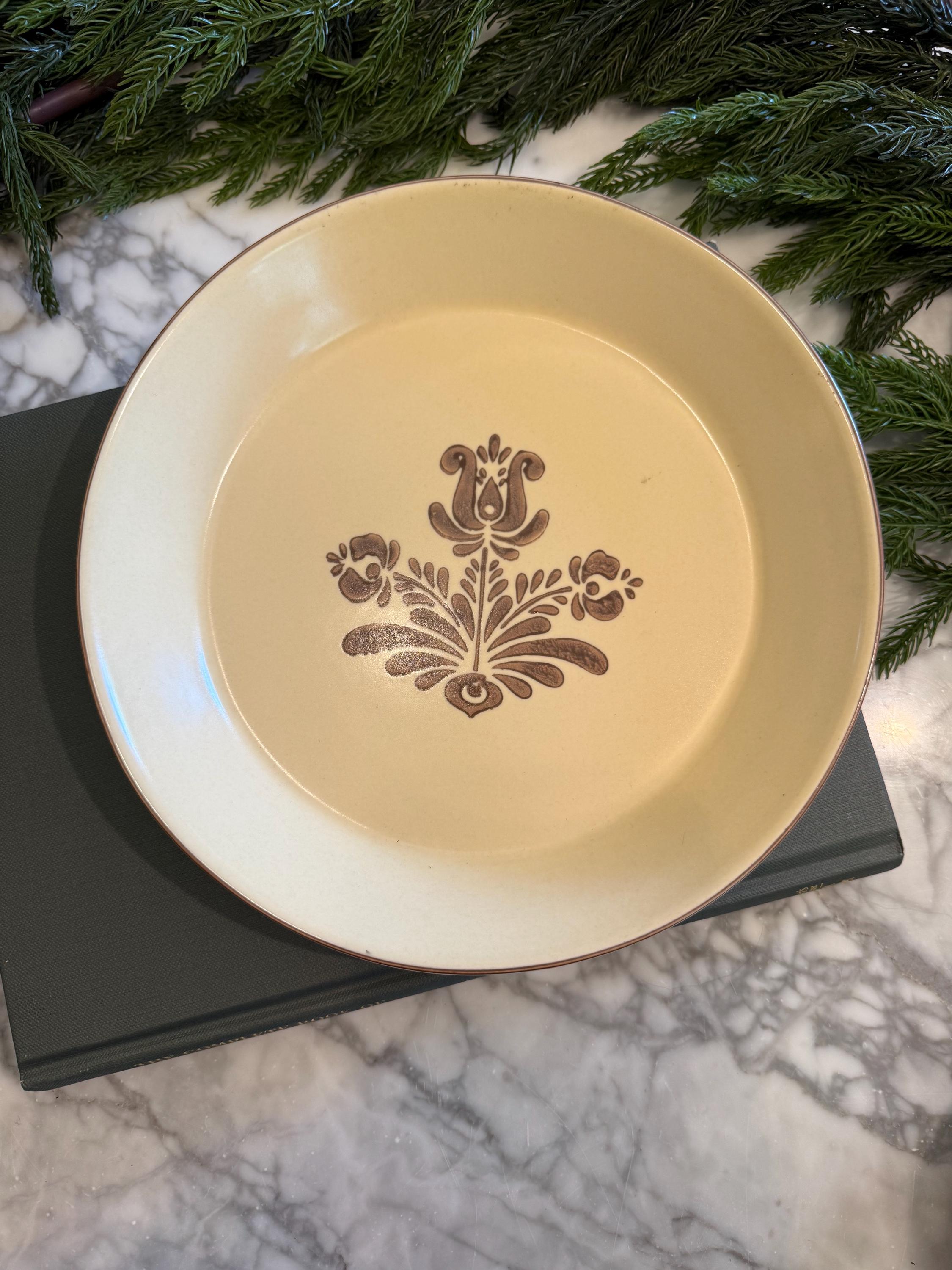 Macro shot of the center of the pie dish, highlighting the crisp, dark brown folk-art floral pattern characteristic of the 1970s Pfaltzgraff Village collection.