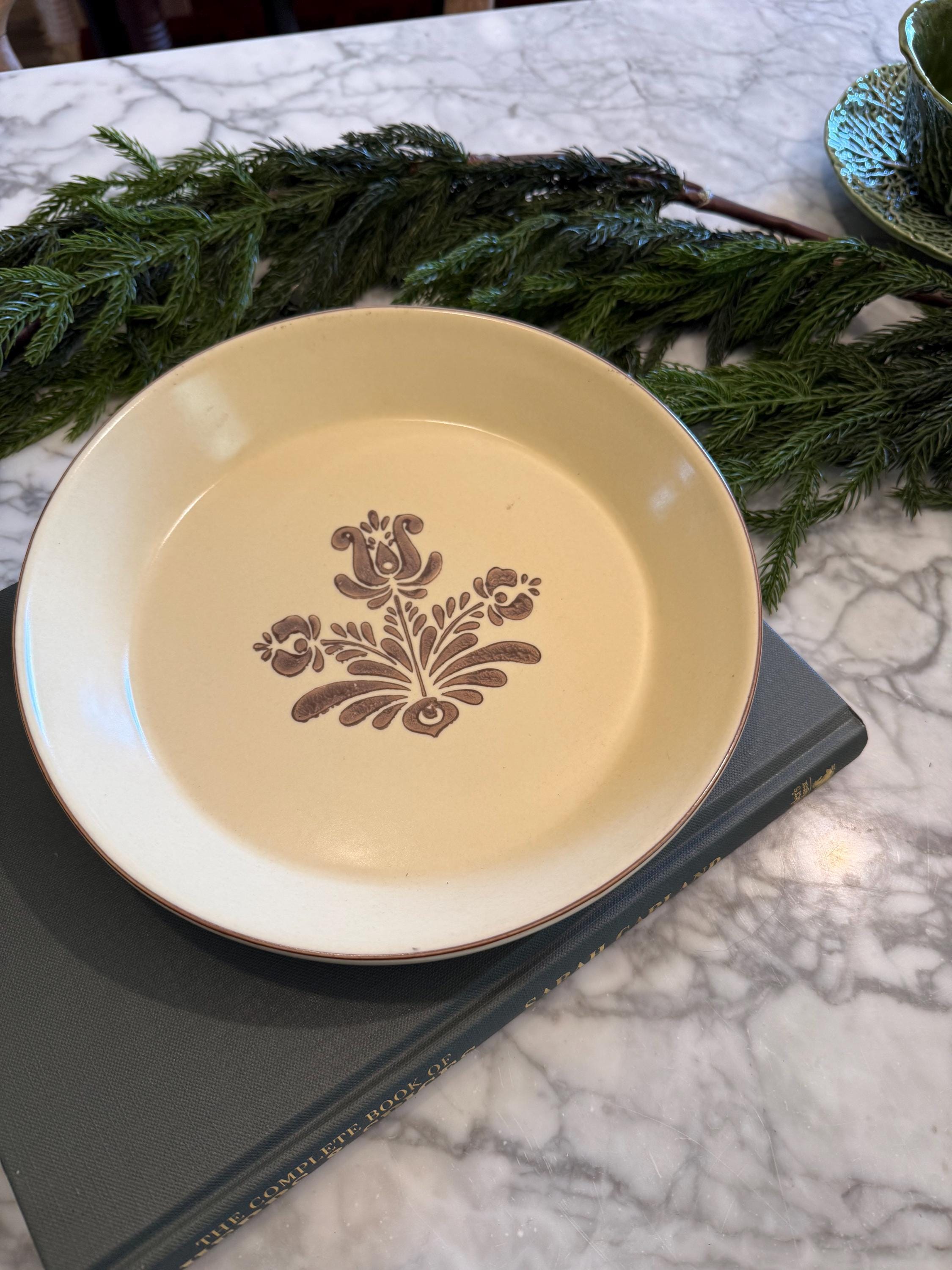 Close-up profile view of the Pfaltzgraff Village 9-inch pie dish, showcasing the fluted rim detail, sturdy stoneware thickness, and cream-colored glaze.
