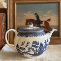 Classic Johnson Bros Blue Willow blue and white ironstone teapot on a white linen cloth