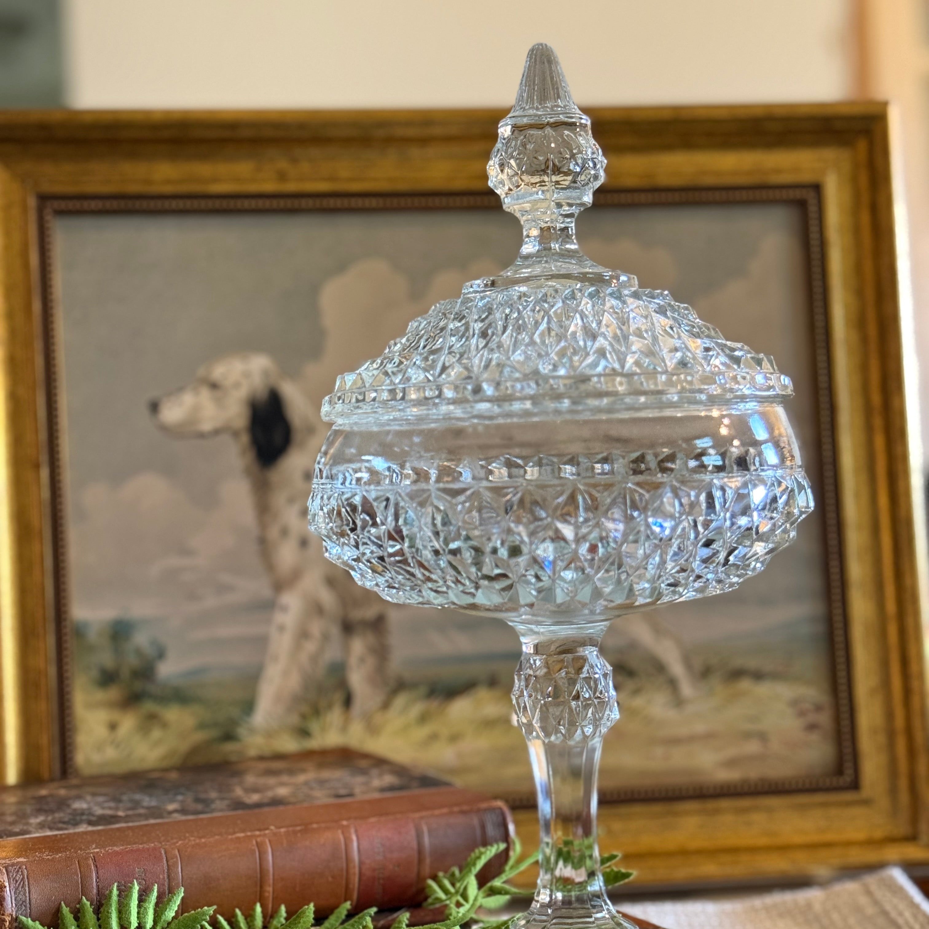 Crystal Indiana glass vintage dish on a wooden stand with a framed painting of a dog in the background