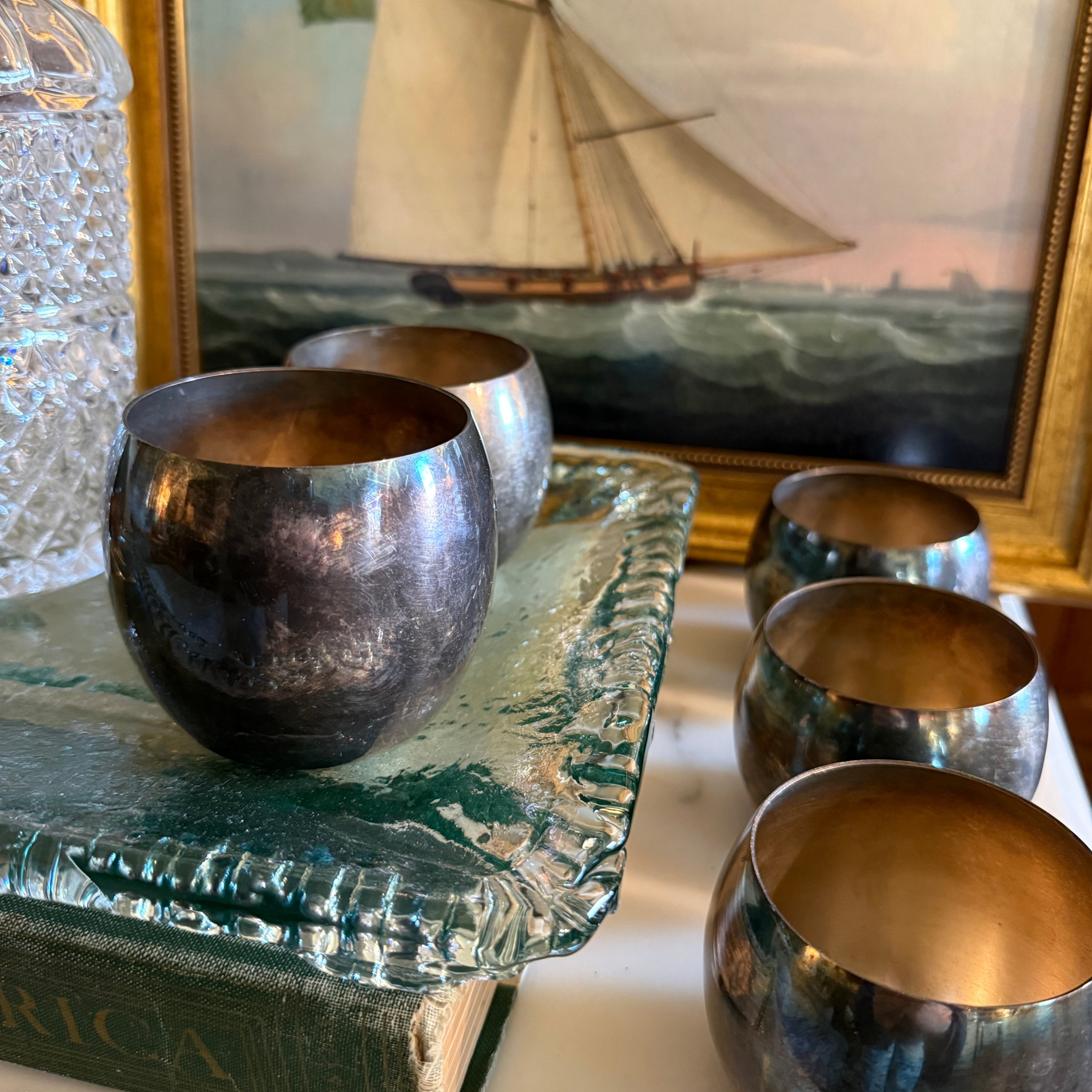 Set of 5 vintage Poole EPCA silverplate roly poly goblets with heavy dark tarnish on a vintage book