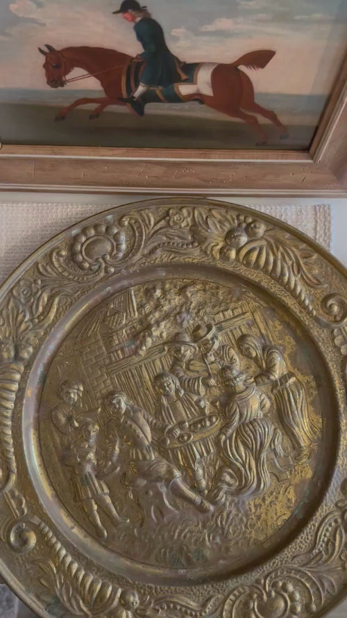 upclose of english brass wall plate with a tavern depiction 