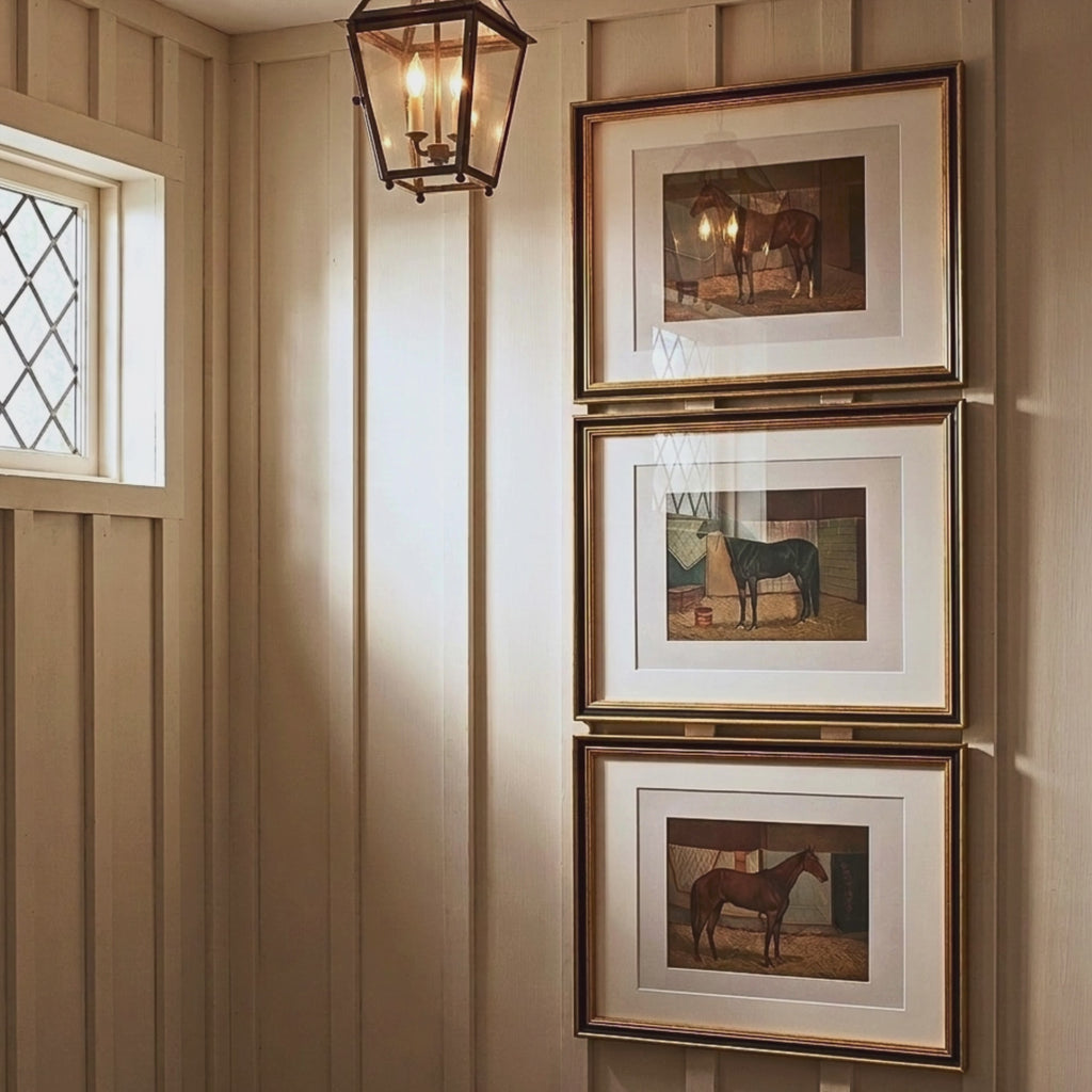 Video showing a stacked gallery wall featuring three ornate gold framed vintage racehorse prints in a sunlit entryway
