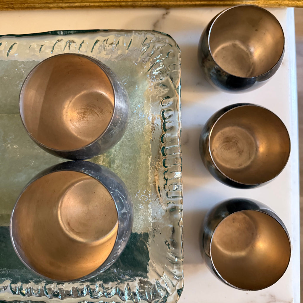 Top view of five tarnished silver roly poly cups showing interior and exterior patina.