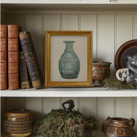 Sophisticated bookcase styling featuring a vintage leather bound books with trinkets and moss on shelf.