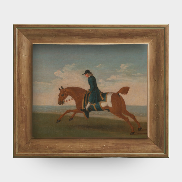 A reproduction of a chestnut racehorse with a trainer in a blue coat, framed in natural English pine.