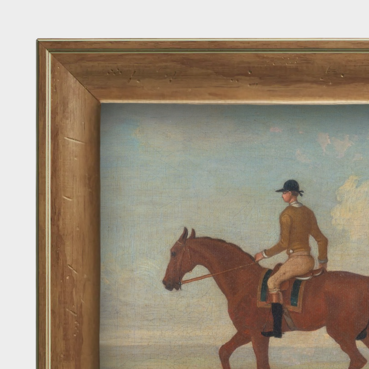 Detail shot of the natural English pine frame grain and the tactile linen texture of the jockey portrait.