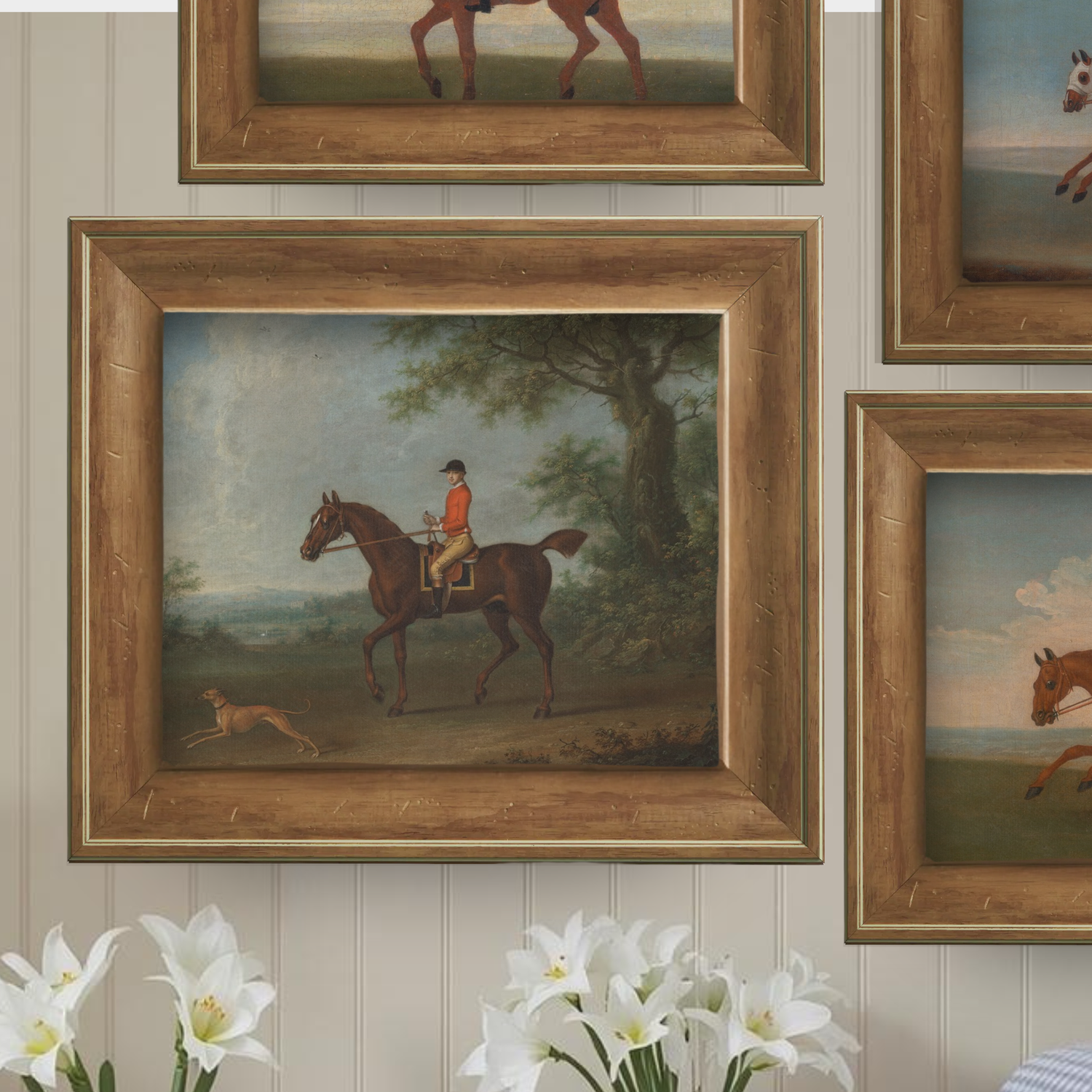 Framed paintings of equestrian scenes styled on a gallery wall with white flowers in the foreground.