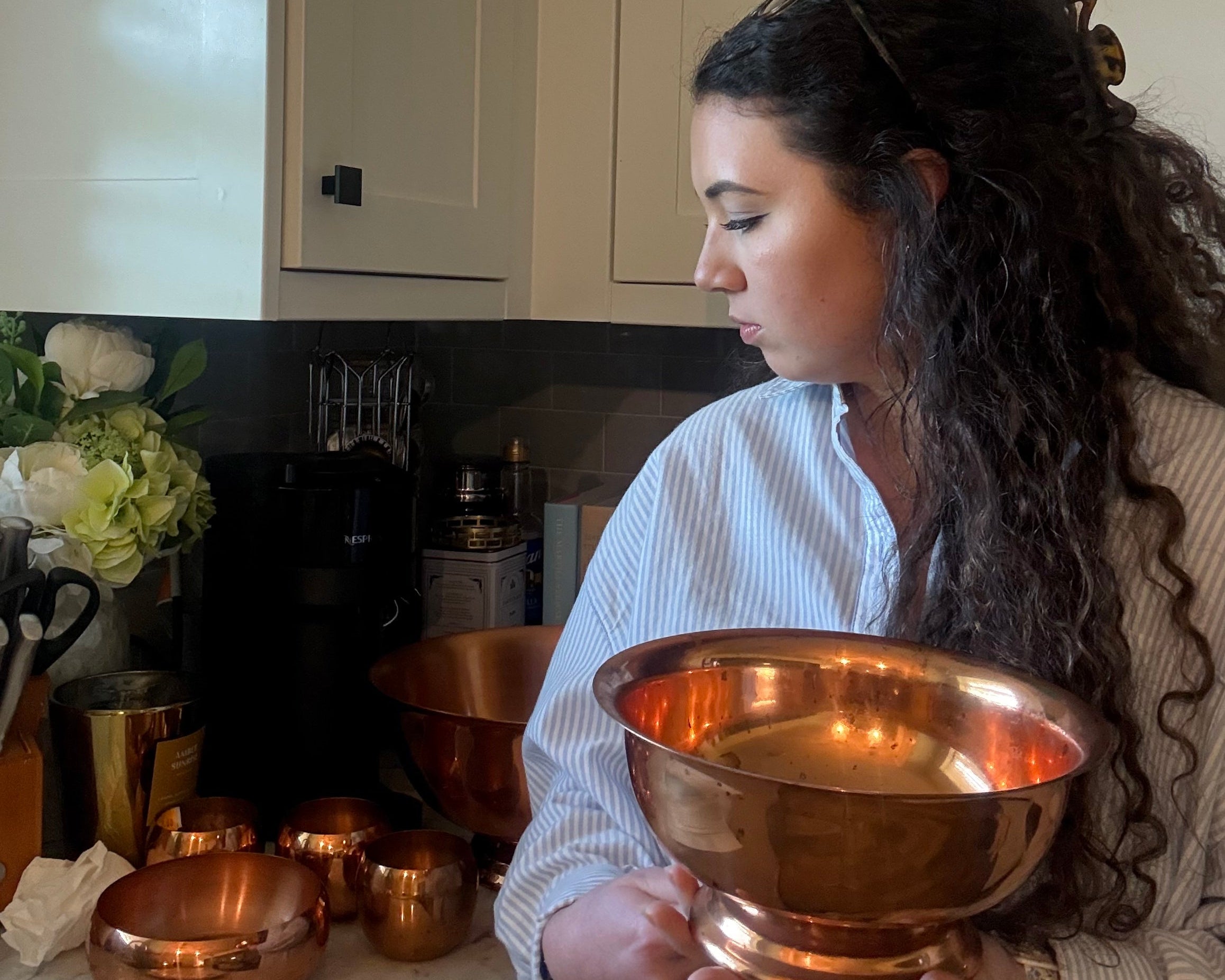 Person holding a large copper bowl in a kitchen setting