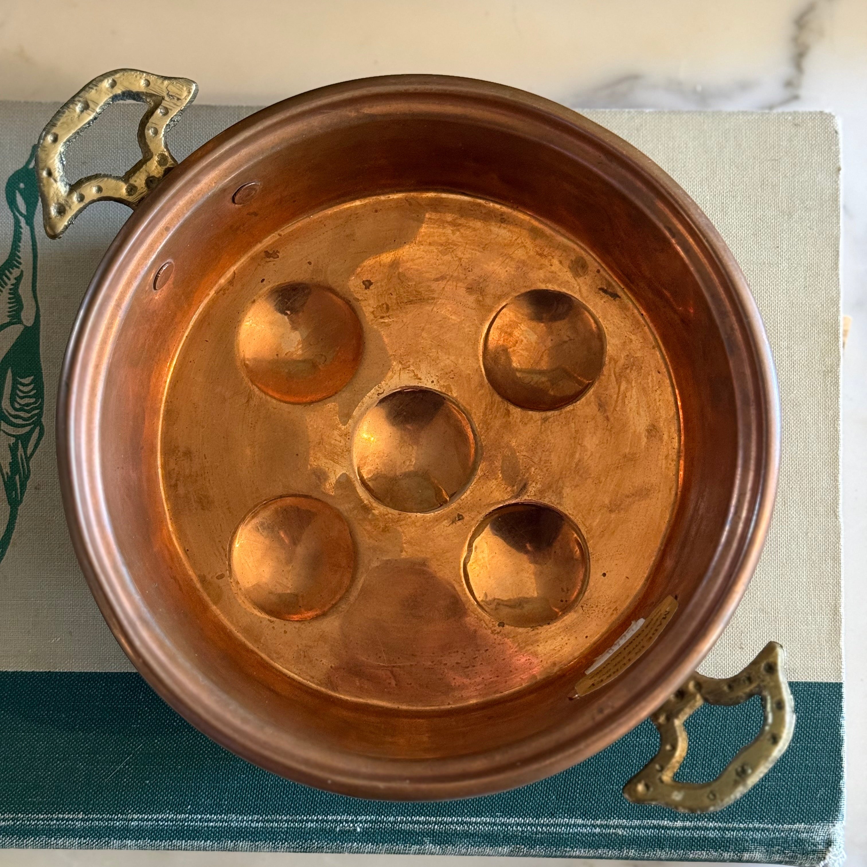 Interior view of a 5-hole copper egg poaching pan showing the hammered texture.