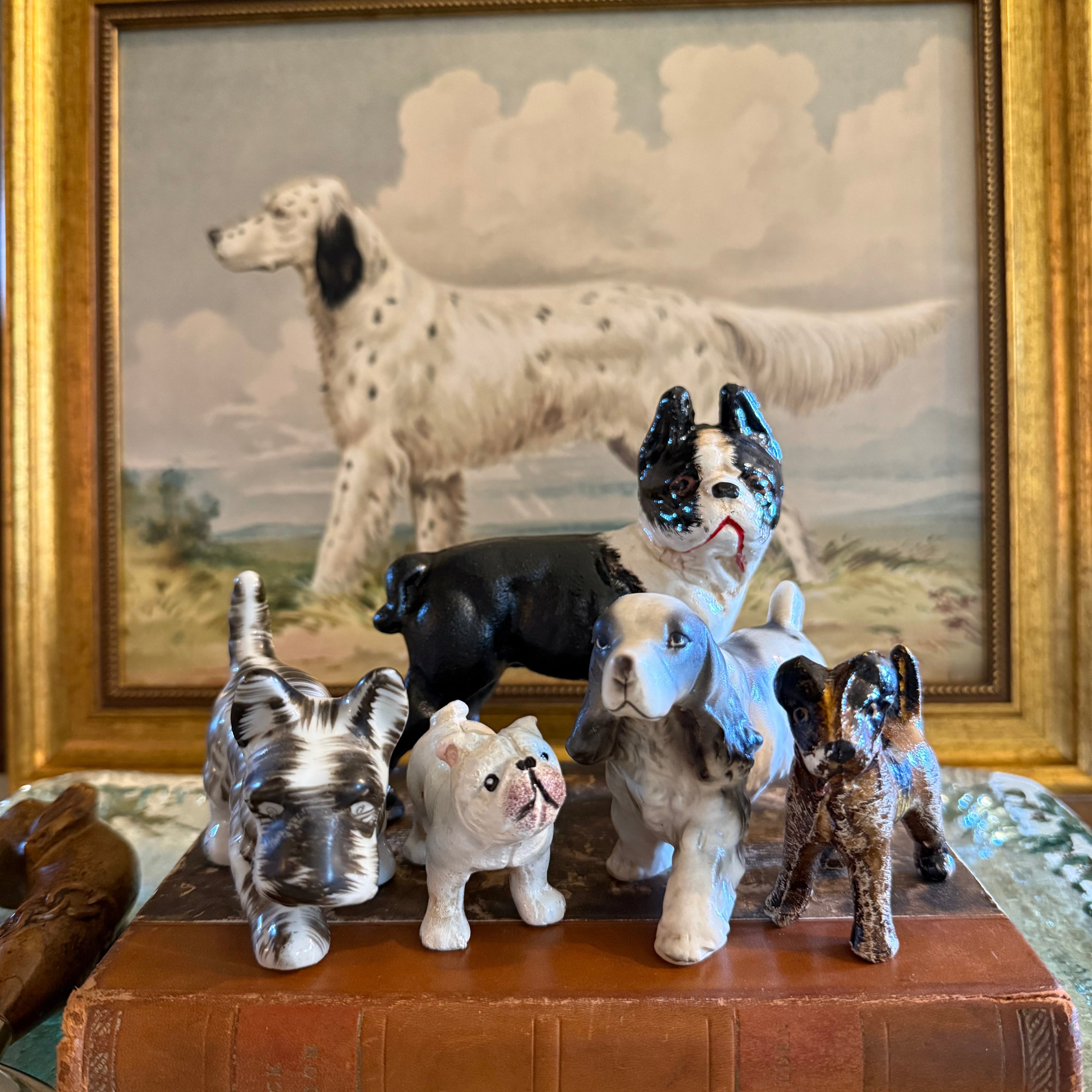 Decorative dog wall art with small vintage dog figurines on a leather bound book.